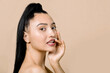 © sofiko14 - Beautiful young asian girl with clean fresh skin and natural nude makeup, looks at camera with sexy smile, touching her lips, posing on beige background. Facial treatment, beauty and spa. Copy space