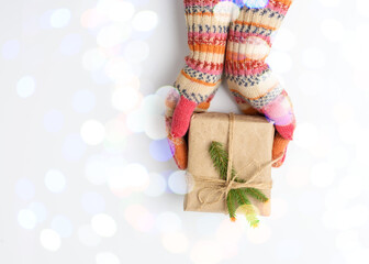 Wall Mural - female hands in knitted mittens hold a box in brown paper and tied with a rope