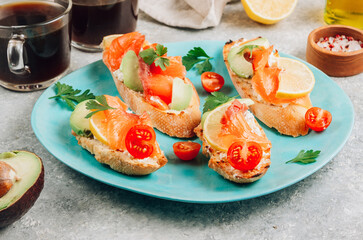 Wall Mural - Smoked salmon sandwich with cream cheese, lemon, avoado and tomato on gray background.