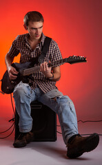 The guitarist play music with combo amplifier in beautiful red hall.  