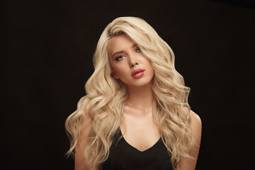 Wall Mural - Attractive adult girl with long blonde hair and natural clean skin posing on a black isolated background.