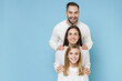 © ViDi Studio - Smiling young happy parents mom dad with child kid daughter teen girl in basic white sweaters stand behind each other isolated on blue color background studio portrait. Family day parenthood concept.