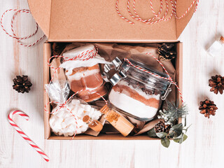 Christmas gift box with cookie mix and chocolate drink in glass jar on dark wooden table. Layers of flour, cocoa powder, sugar. Ingredients for ginger bread. Copy space for your text