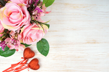 Pink rose bouqet and red two hearts on white wooden background. Top view, flat lay with space for text.