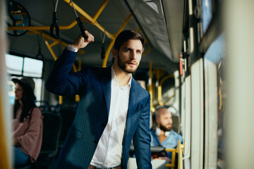 Wall Mural - Businessman looking through the window while traveling by public bus.