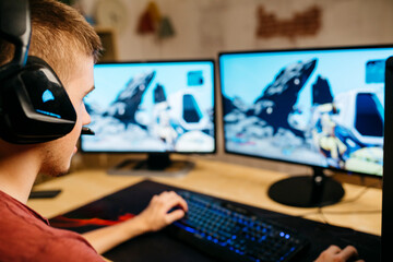 Young man playing video games with computer at desk