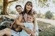 © Mareen Fischinger/Westend61 - Mother embracing sons while sitting in public park