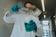 © Mareen Fischinger/Westend61 - Scientist mixing liquid solution in flask while standing at clinic corridor