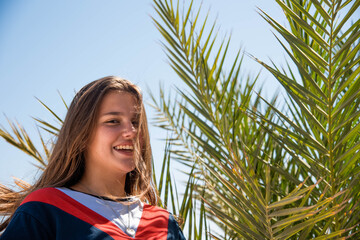 Wall Mural - woman wearing sunglasses posing with palm tree. Portrait of beautiful teenage girl