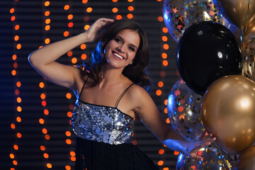 Sticker - Happy woman with air balloons against blurred festive lights. Christmas party