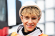 © Westend61 - Smiling blond male teenage trainee wearing hardhat at construction site