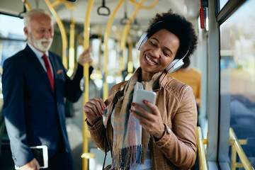 Wall Mural - Happy African American woman listening music while commuting by public transport.