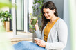 © UWE_UMSTAETTER/Westend61 - Young woman using mobile phone while drinking smoothie at home