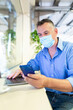 © William Perugini/Westend61 - Male entrepreneur wearing protective face mask while using smart phone at coffee shop