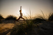 © UWE_UMSTAETTER/Westend61 - Silhouette young woman practicing warrior position yoga amidst plants at beach against clear sky during sunset