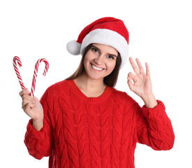 Canvas Print - Pretty woman in Santa hat and red sweater holding candy canes on white background