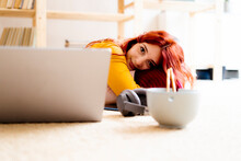 Young Woman Lying On Carpet By Laptop At Home