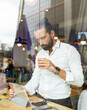 © Jose Carlos Ichiro/Westend61 - Candid portrait of bearded businessman drinking coffee in front of digital tablet inside cafe