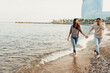 © VALENTINA BARRETO STUDIO/Westend61 - Happy young couple having fun while walking at beach against clear sky