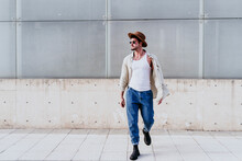 Confident Man In Hat Looking Away While Walking Against Wall