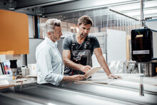 Mature Worker Discussing With Manager Over Document In Factory