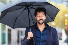 Smiling Entrepreneur Holding Umbrella In City During Rainy Season