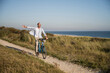 © UWE_UMSTAETTER/Westend61 - Carefree mature man riding bicycle at beach against clear sky during weekend