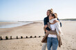© UWE_UMSTAETTER/Westend61 - Young couple with eyes closed embracing while standing at beach against clear sky