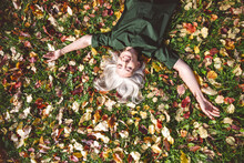 Mature Woman Smiling While Lying On Grass At Park