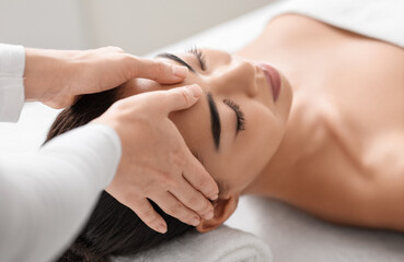 Wall Mural - Spa therapist making relaxing head massage for beautiful asian woman in salon