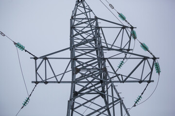 High-voltage tower on the background of the sky in winter in the snow.