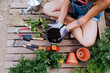 © Eva Blanco/Westend61 - Mid adult woman holding dirt in flower pot while sitting on wood at vegetable garden