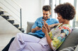 © klublu/Westend61 - Cheerful diverse couple using smartphones on couch