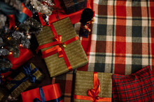 Photo Of Wrapped With Paper Red Ribbon Gift Boxes Presents Laying On Soft Checkered Blanket Under Christmas Tree