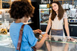 © Giorgio Fochesato/Westend61 - Happy female owner selling coffee to woman in coffee shop