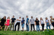 © Eugenio Marongiu/Westend61 - Group of friends standing side by side on grassy land against sky in park
