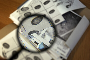 Sticker - Fingerprint card on table, view through magnifying glass. Detective work