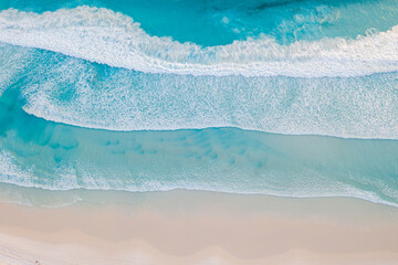 Wall Mural - top down view of waves crashing against an empty beach. 