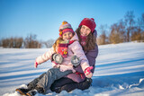 Fototapeta Nowy Jork - Little girl and her mother playing outdoors at sunny winter day. Active winter holydays concept.