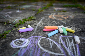 Children's drawing and colored chalks on a tile.