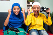 © WESTOCK - Point of view shot, Two muslim kids cheering and shouting after won the online video game while playing with joystick or gamepad at home sitting on sofa.