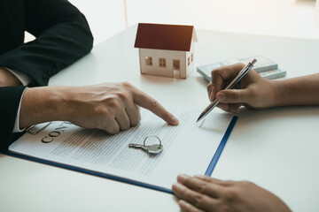 Wall Mural - New home buyers are signing a home purchase contract at the agent's desk.