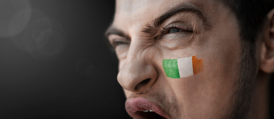 A screaming man with the image of the Ireland national flag on his face