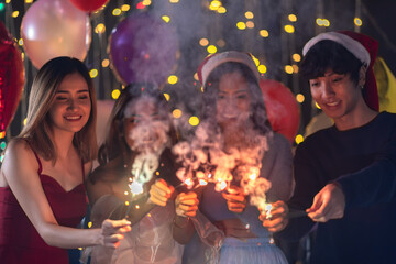 Happy friends celebrating with sparkler fireworks on new year's eve 2021- Different age of people having fun together in patio home party doing selfie - Winter and holidays concept