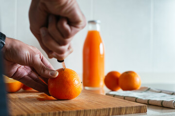 Close up man cutting an orange and making juice