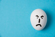 © queen1987 - Egg with a disgruntled, angry face. Isolate on a blue background.
