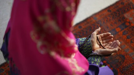 Wall Mural - Closeup of a muslim woman hands while praying with prayer beads on prayer rug.