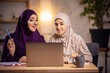 © master1305 - Emotions. Happy and young two muslim women at home during lesson, studying near computer, online education. Culture, traditions, modern people. Watching at PC monitor, shopping or talking.