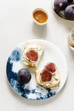 Fototapeta  - Two Sandwich with Ricotta and fresh Figs sprinkled honey on plate on grey concrete background. Simple healthy breakfast