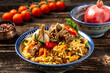 © Надія Коваль - Traditional uzbek meal called pilaf. Rice with meat, carrot and onion in plate with oriental ornament, Uzbek oriental cuisine. Long banner format. space for text